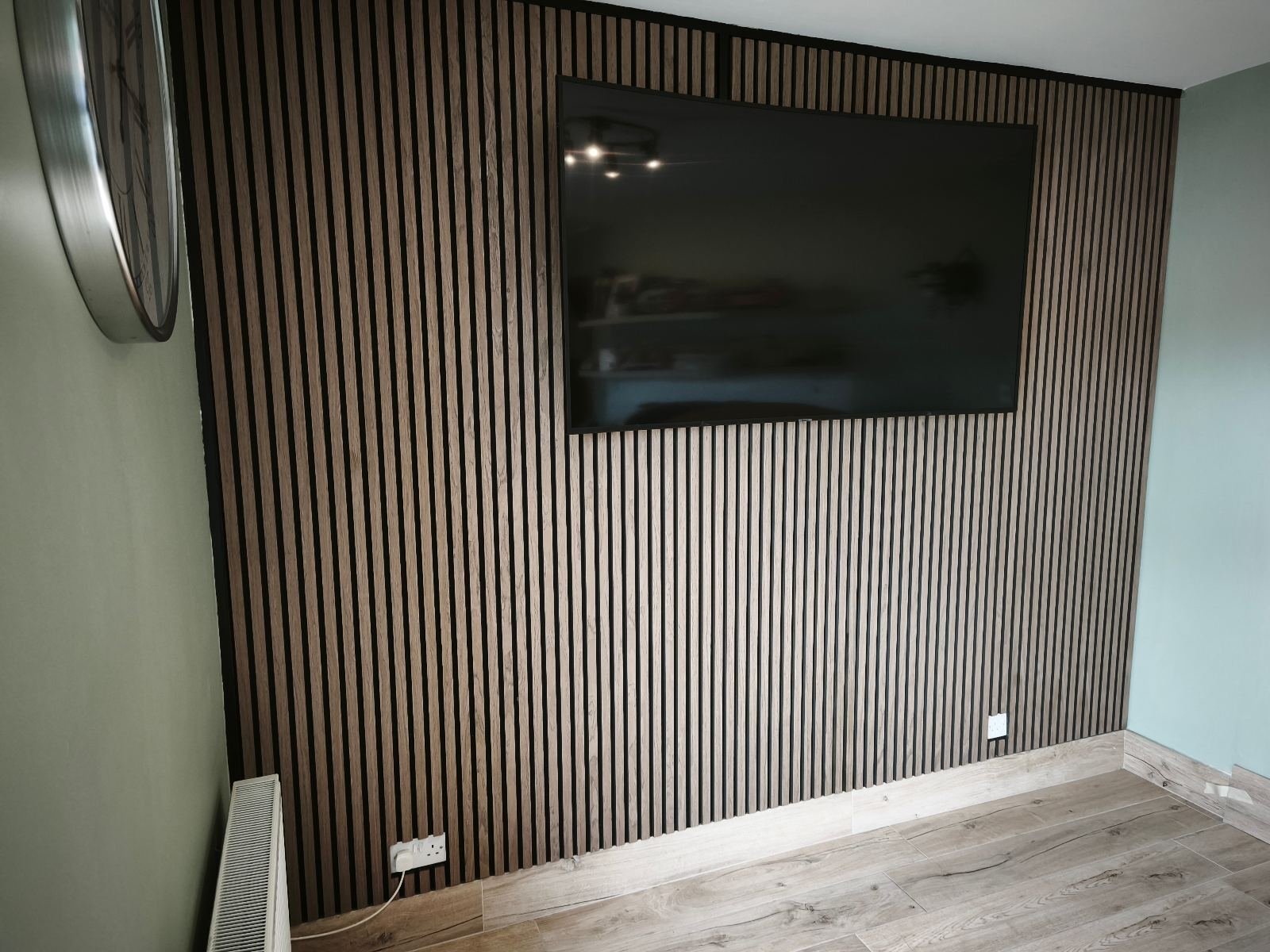 Acoustic slat panel TV wall fitted in a Dublin living room, oak slats on black felt