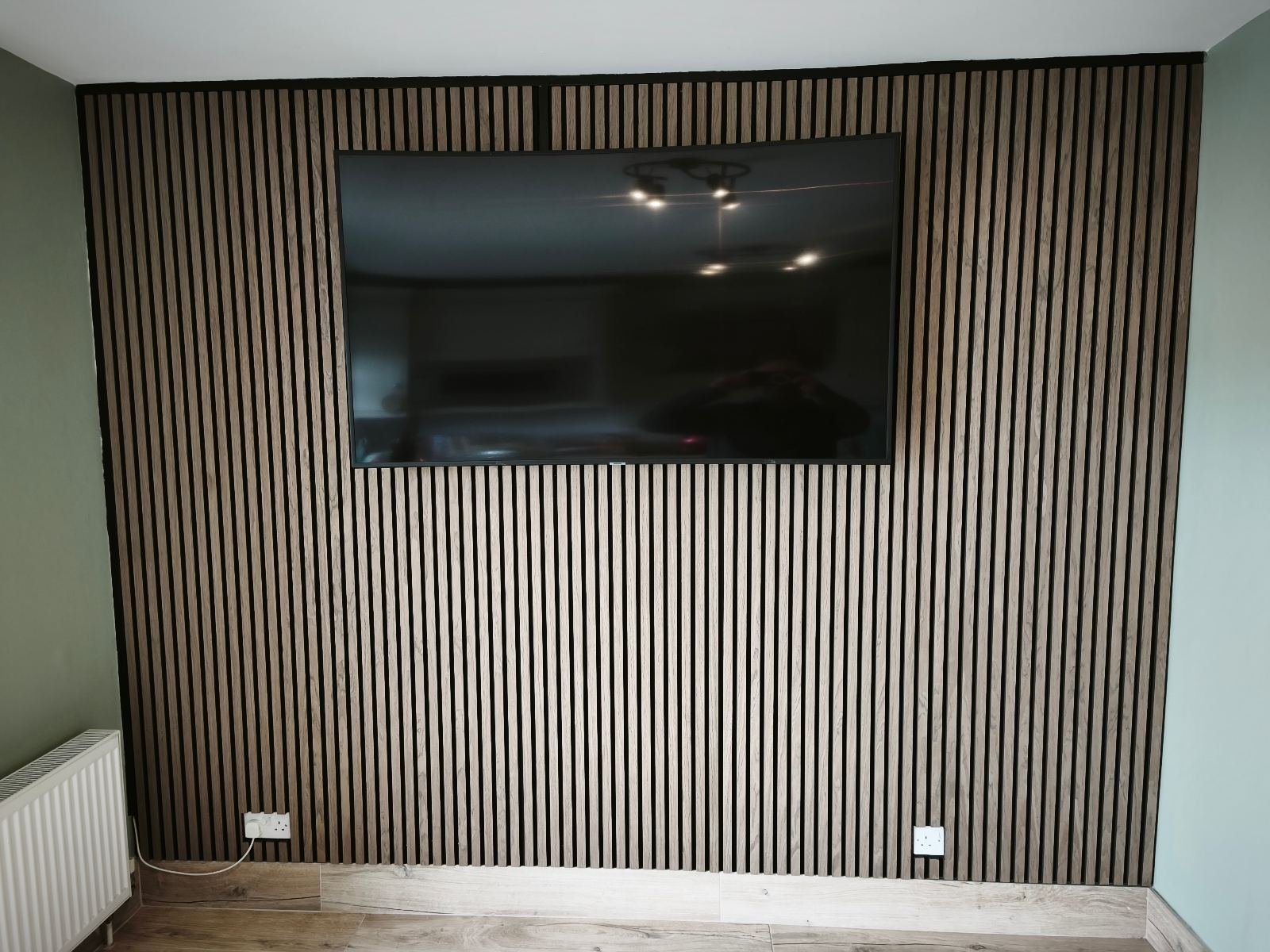 Full-height acoustic slat wall around a wall-mounted TV, Dublin