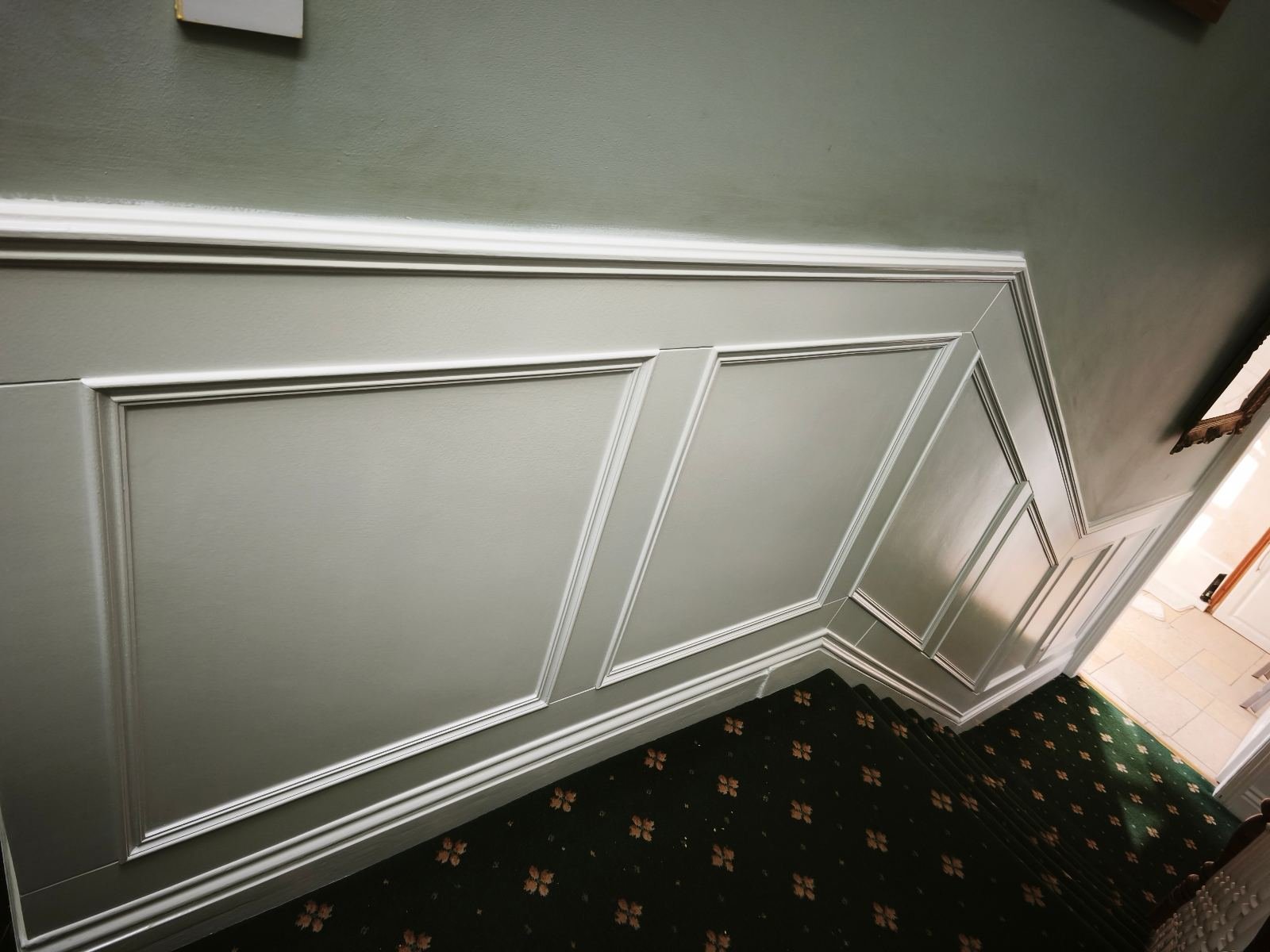 Recessed panel panelling on a Dublin staircase wall, painted sage green with mouldings recessed inside each panel