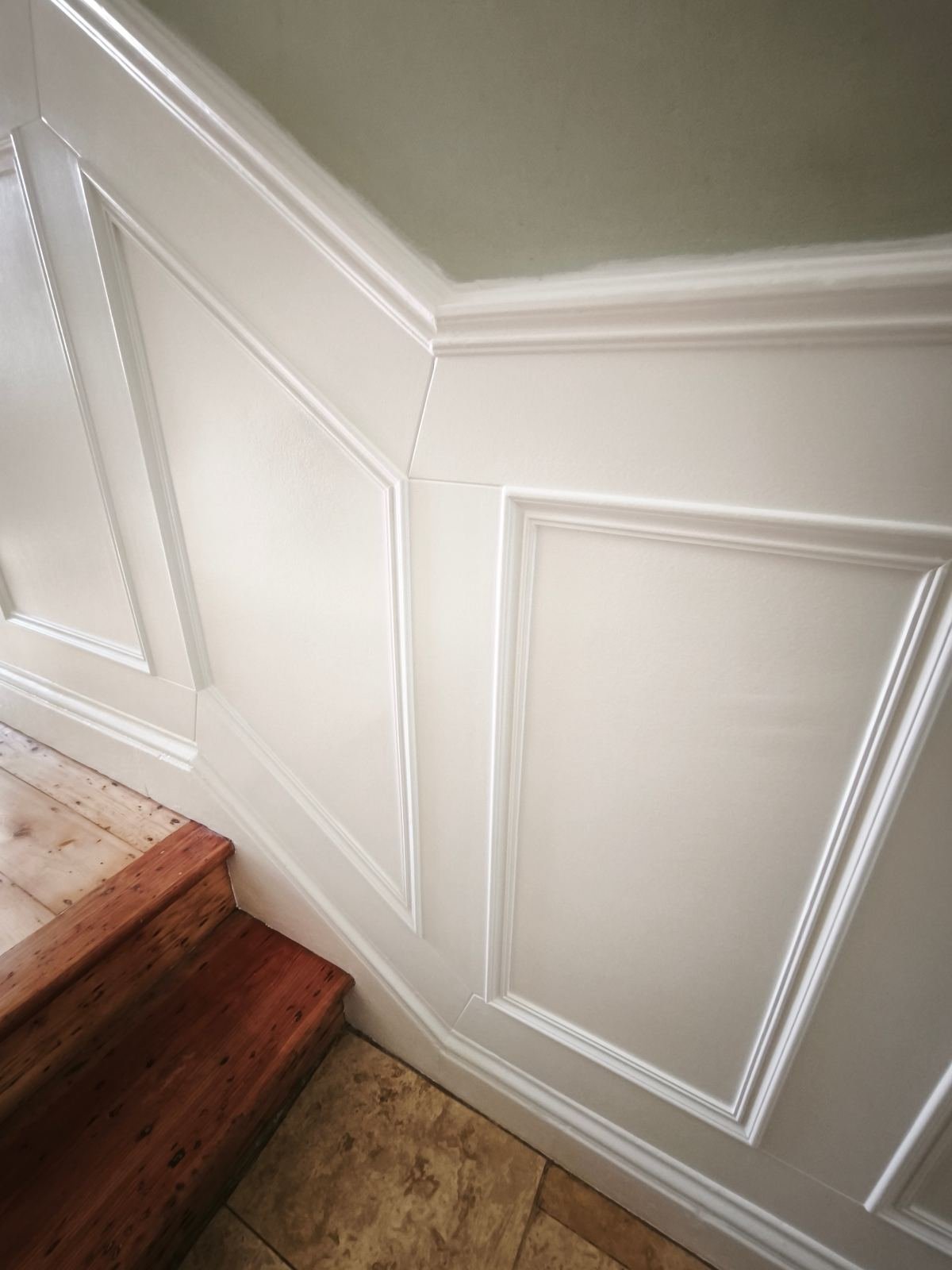 Recessed panelling turning the corner on a Dublin stairs, painted white with a crisp mitred dado cap