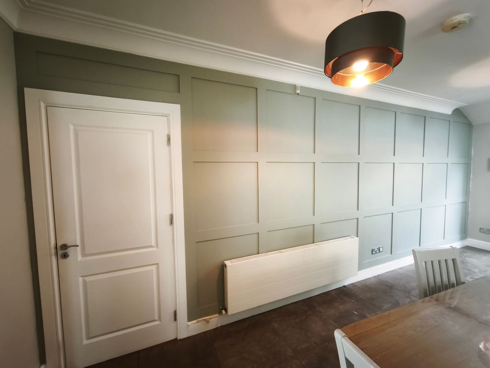 Full-height shaker panelling in a Dublin dining room, painted sage green and set out around the door and radiator